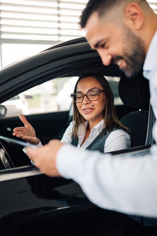 Woman discussing in car with a salesman in a car dealership