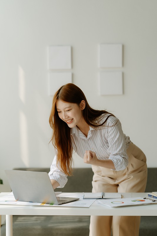 Asian Business woman using calculator and laptop for doing math finance on an office desk, tax, report, accounting, statistics, and analytical research concept